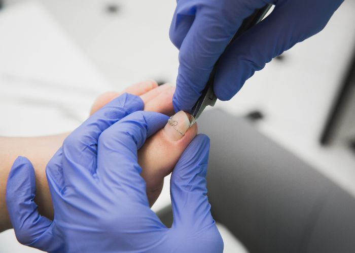 Präzise Nagelpflege mit professionellem Werkzeug und Schutzhandschuhen.