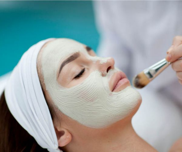 Frau erhält eine pflegende Gesichtsbehandlung mit einem Pinsel.